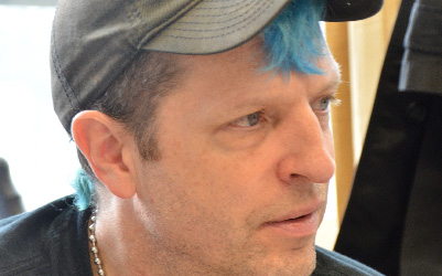 White man wearing a baseball cap with blue hair.