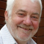 White man with white hair and beard smiling.
